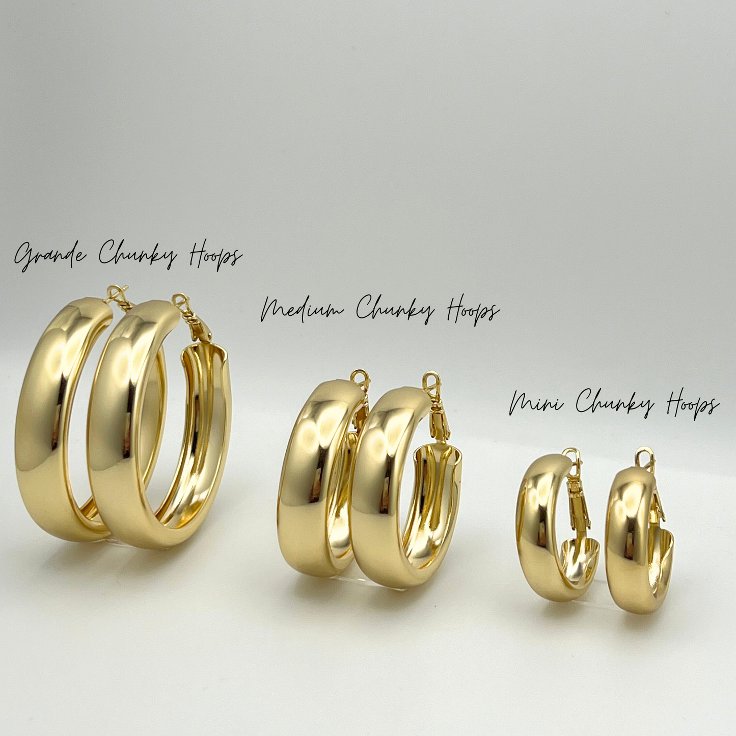 A gold chic and chunky hoop earring in three different sizes: grande, medium and mini