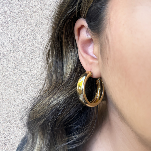 Models ear wearing a medium sized chunky gold hoop earring