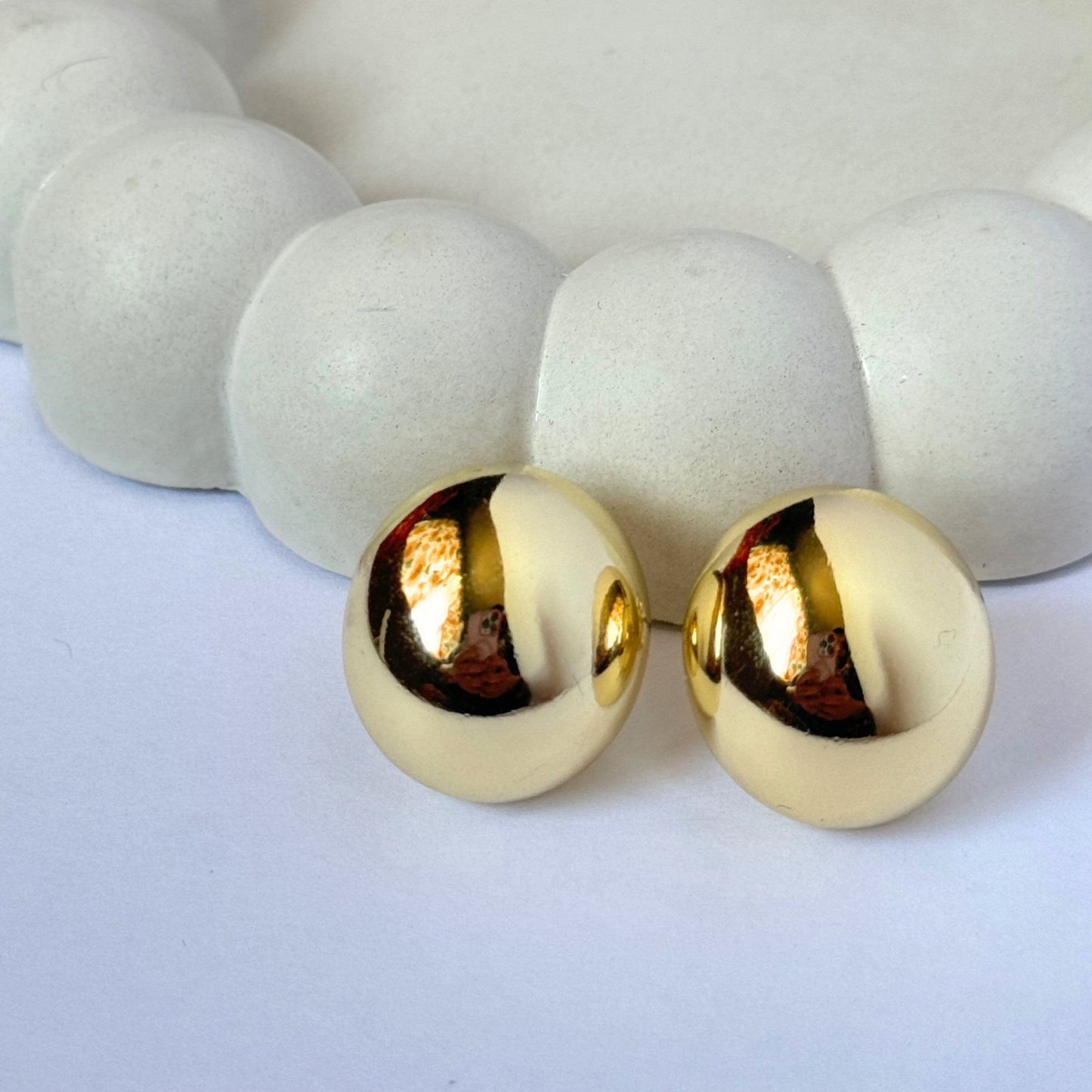 chunky gold filled half dome earring displayed on beige concrete bubble jewelry dish