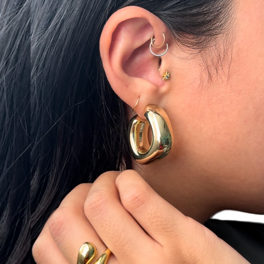 close up image of a model's ear showcasing a chunky gold filled geometric earring shaped like a square hoop