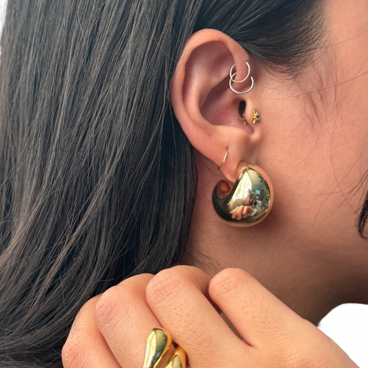 Close up image of a model's ear showcasing a chunky gold filled moon shaped earring.