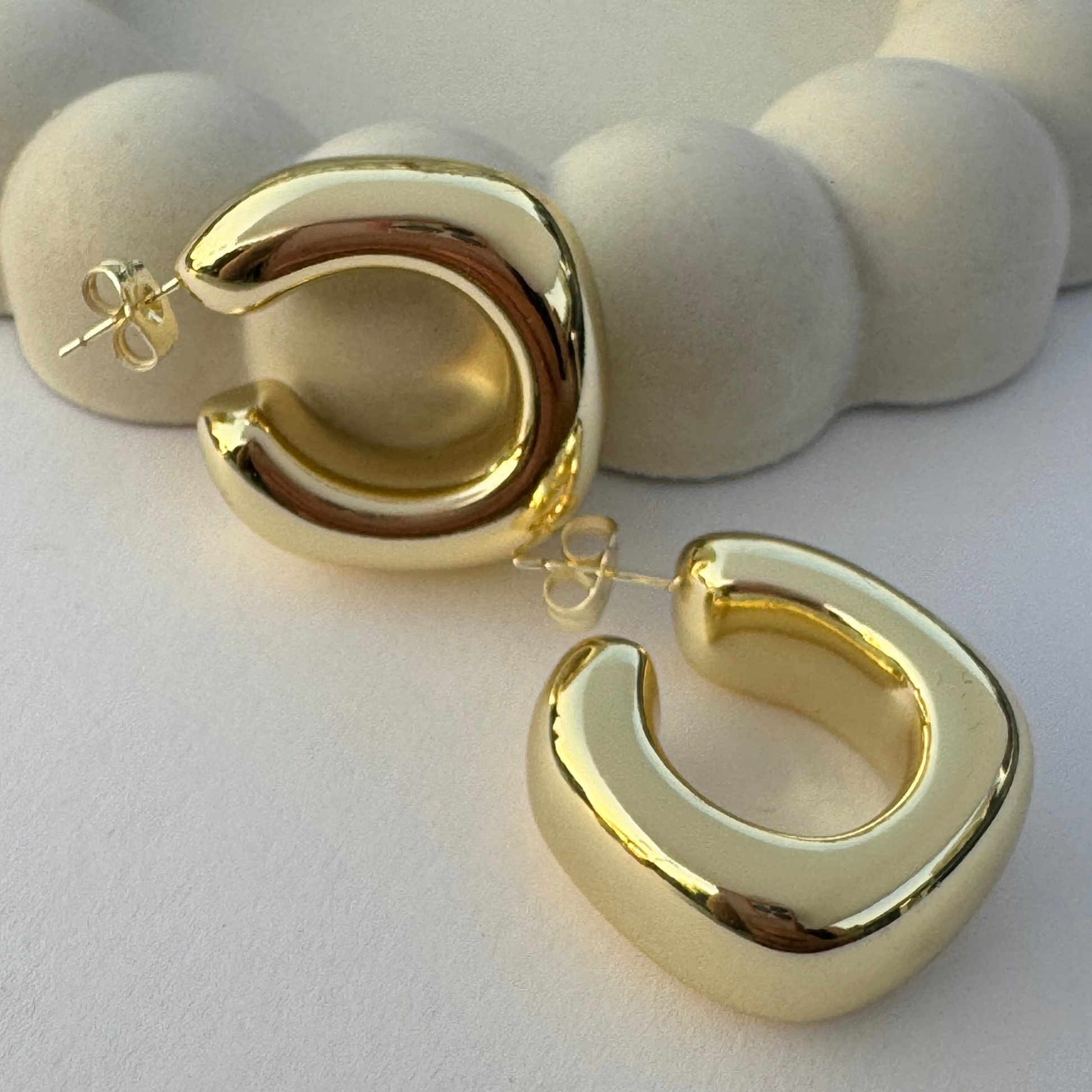 gold filled earrings with unique geometric shape displayed on a beige concrete bubble jewelry dish