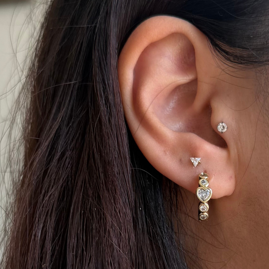 Close-up of an ear with a heart and with round cubic zirconias 