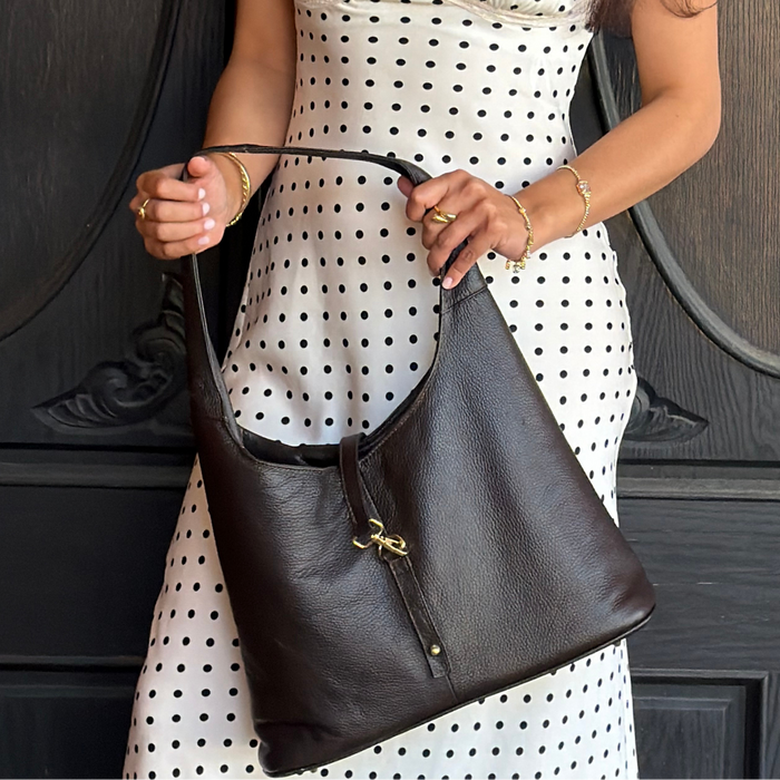 Person holding a black handbag wearing a polka dot dress.