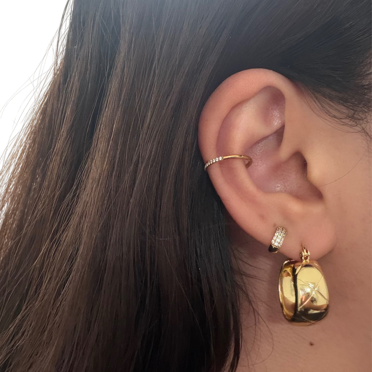 close-up of an ear modeling a gold pair of hoop earrings
