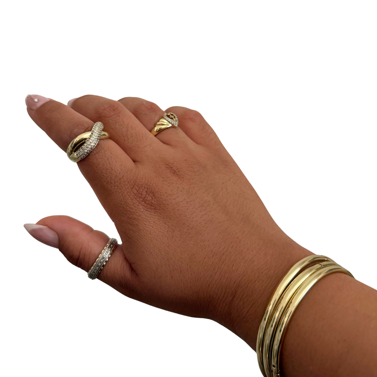 A hand wearing multiple gold rings and a stack of gold bangles against a plain white background.