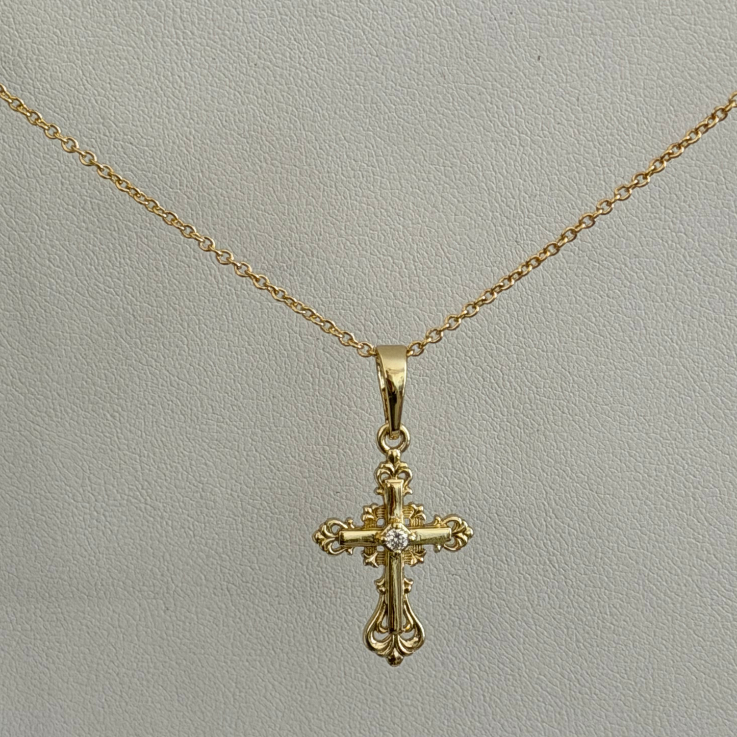 Close product shot of a vintage Catholic inspired cross pendant with a dainty chain 